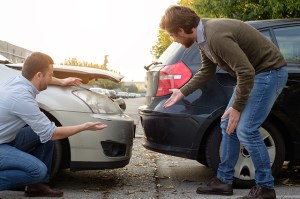 auto insurance fraud - two drivers are inspecting their cars after a accident