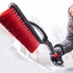 women brushing snow off her windshield - snow and ice removal