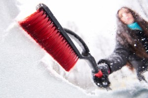 women brushing snow off her windshield - snow and ice removal