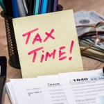 messy desk with tax forms and calculator