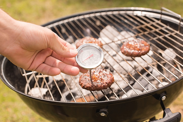 Man using meat thermometer while barbecuing