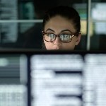 Woman with data on multiple monitors