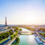 Paris aerial panorama with river Seine and Eiffel tower, France. Romantic summer holidays vacation destination. Panoramic view above historical Parisian buildings and landmarks with blue sky and sun